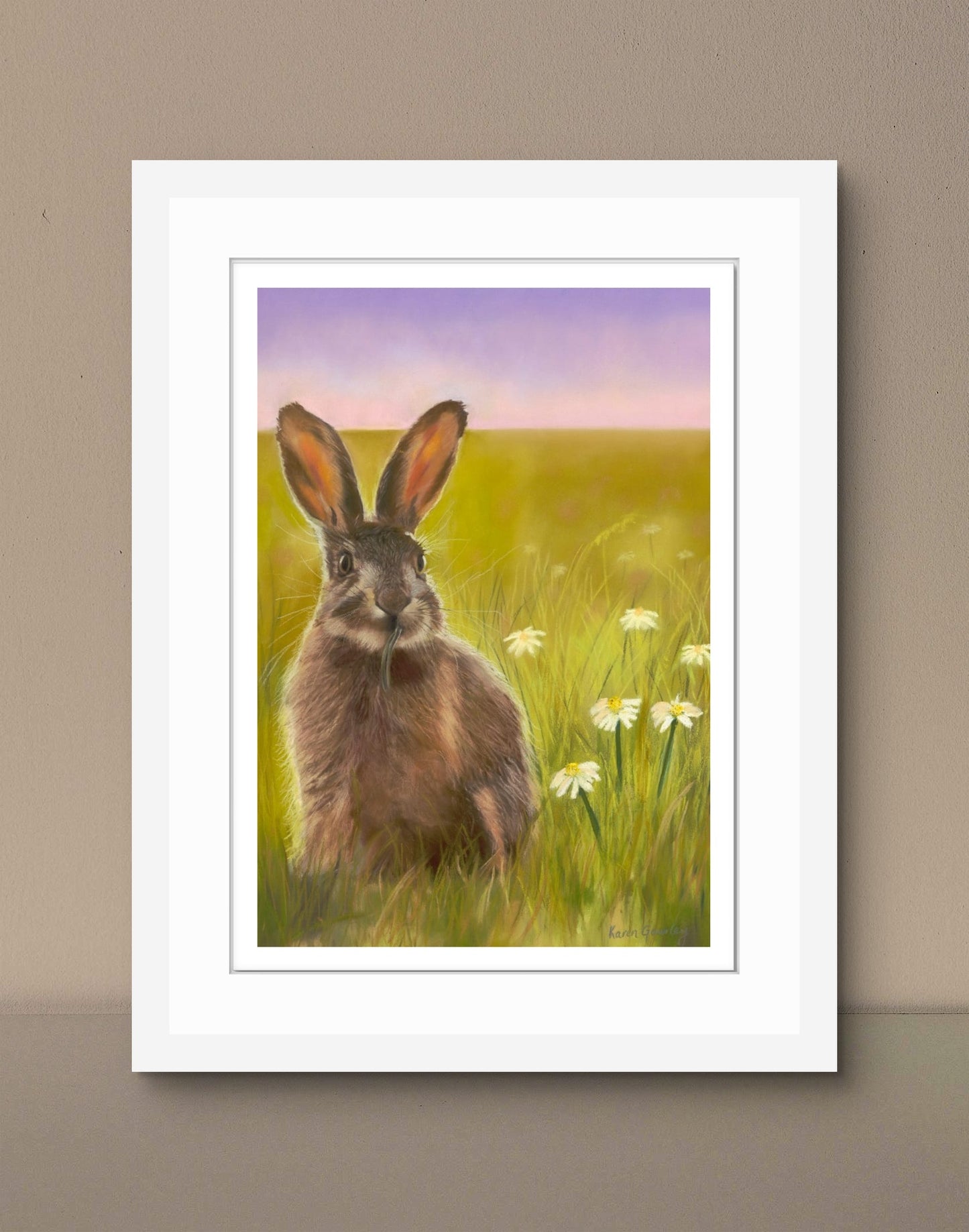 Framed artwork of a hare in a field with flowers on a beige wall.