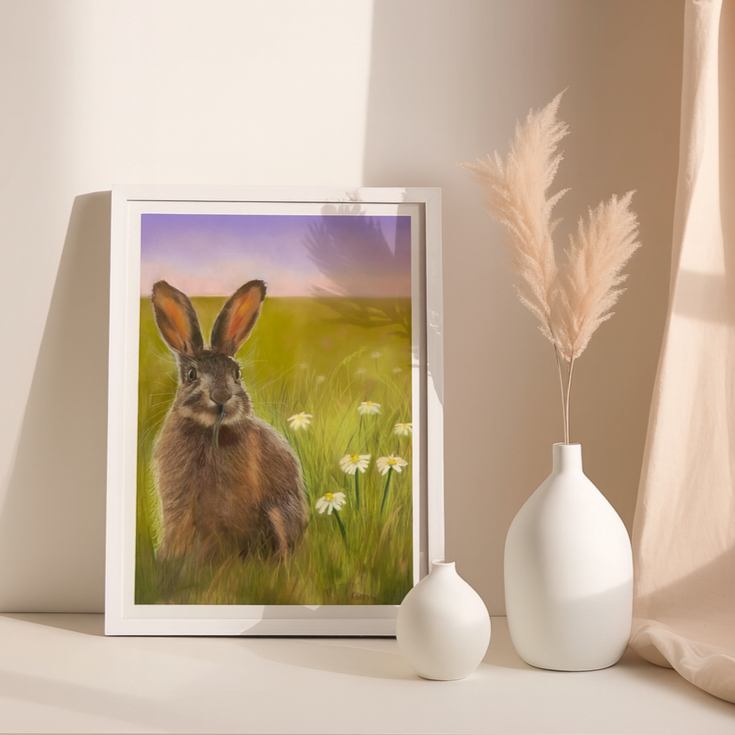 Framed picture of a hare in a field with two white vases on a surface.