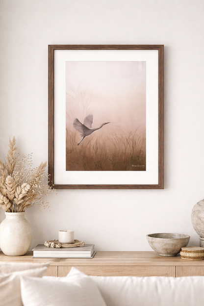 Framed artwork of a bird in a field on a wall above a wooden console table.