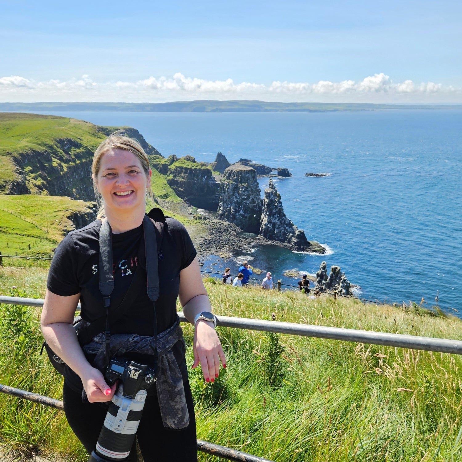 Person standing on a grassy cliff overlooking the ocean with scenic views.