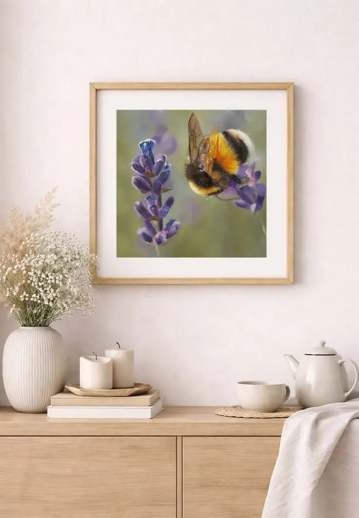 Framed artwork of a bee on a flower above a wooden cabinet with decorative items.