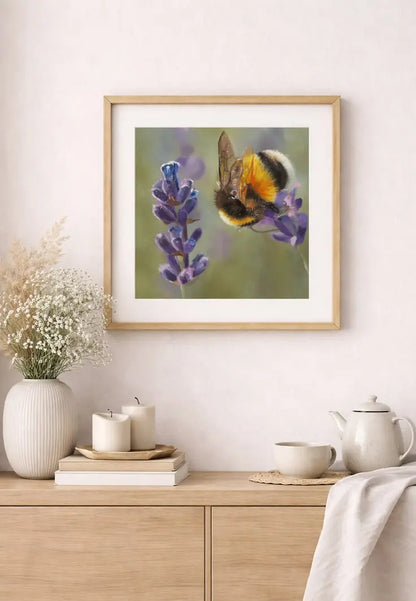 Framed artwork of a bee on a flower above a wooden cabinet with decorative items.