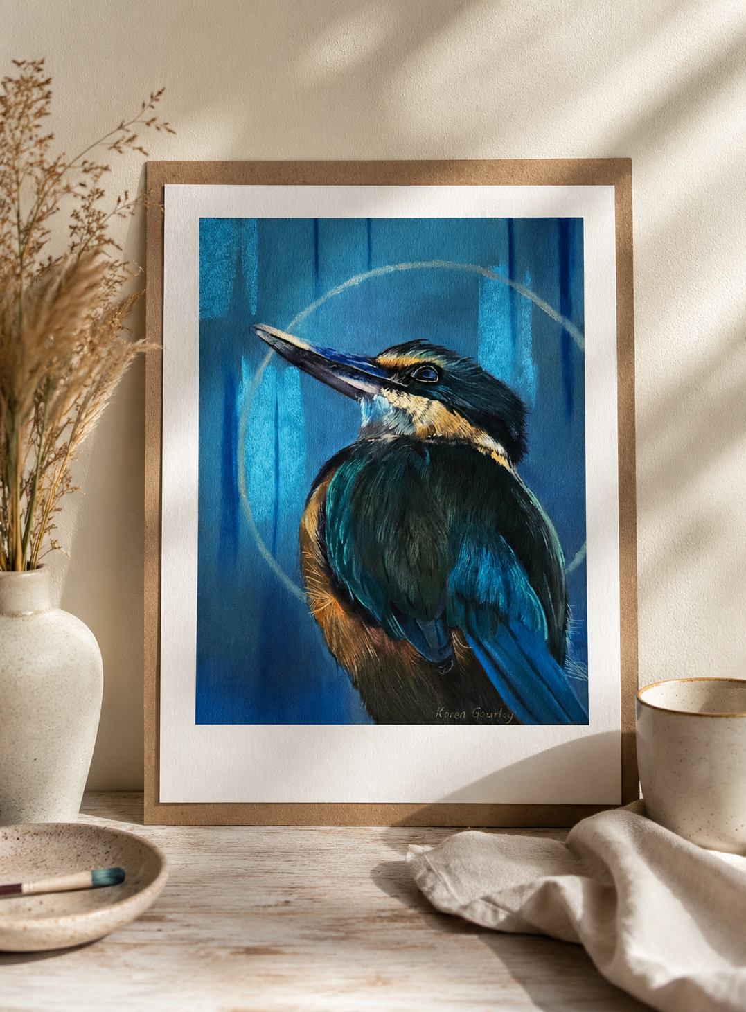 Kotare Sacred Kingfisher fine art print framed and leaning on a sunlit windowsill, styled with dried pampas grass and a stoneware vase